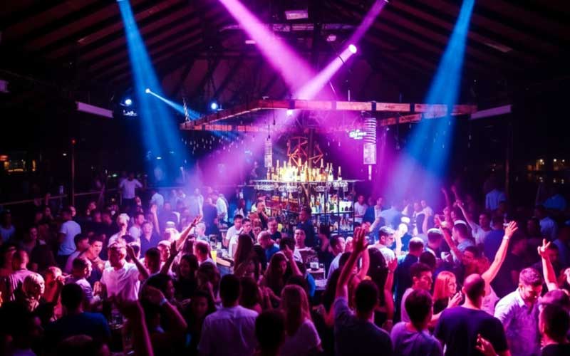 Belgrad’da yüzen bir splav kulüpte renkli ışıklar altında kalabalığın sabaha kadar dans ettiği gece hayatı sahnesi
