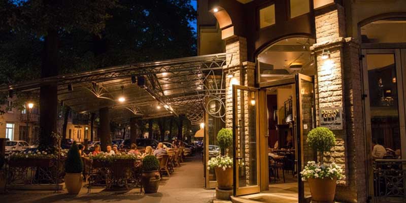 Belgrad Dorćol semtinde akşam ışıkları altında tarihi sokakta dış mekan kafede oturan insanlar