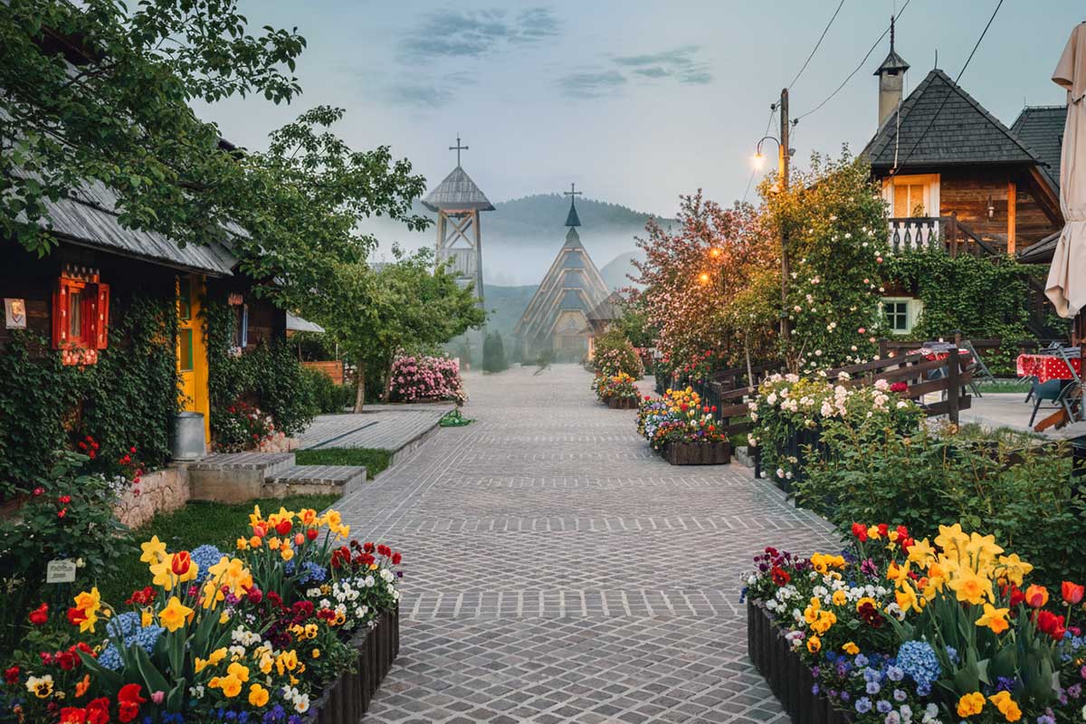 Drvengrad (Mokra Gora) içinde çiçekli sokak ve ahşap yapılar, Sırbistan
